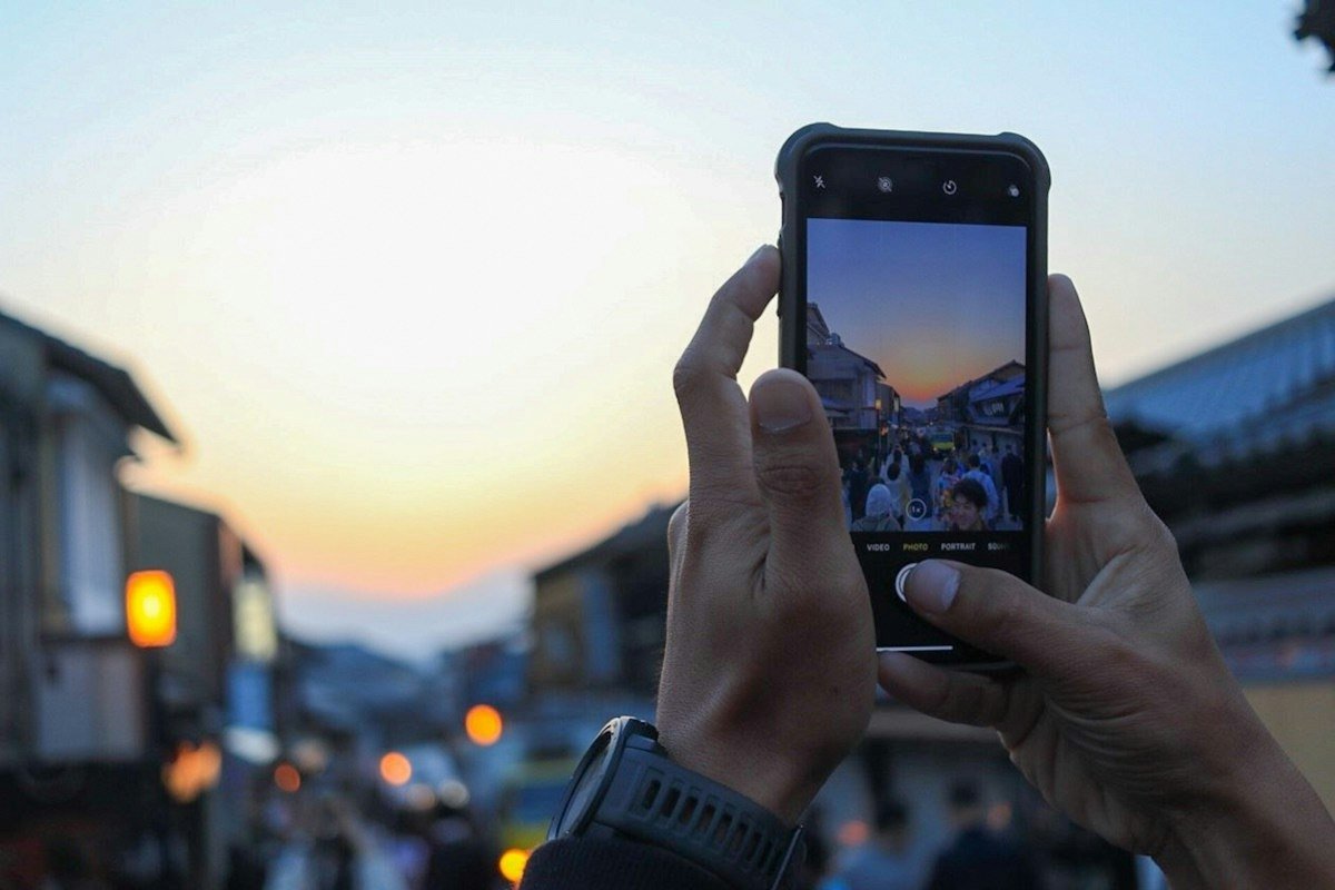 A person using the camera on a smartphone outdoors at sunset