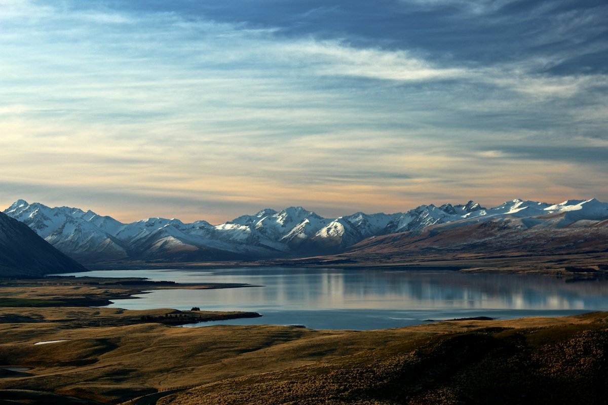 A mountain landscape reflected in a lake under a cloudy sky