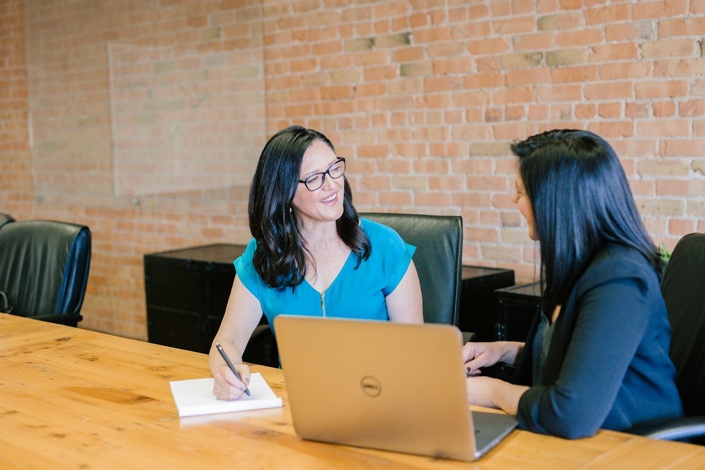 Two people discussing work across a laptop at a table
